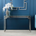 Silver metal console table with tempered glass top styled in a hallway