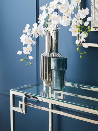 Console table styled with a lamp and vase in a bright foyer