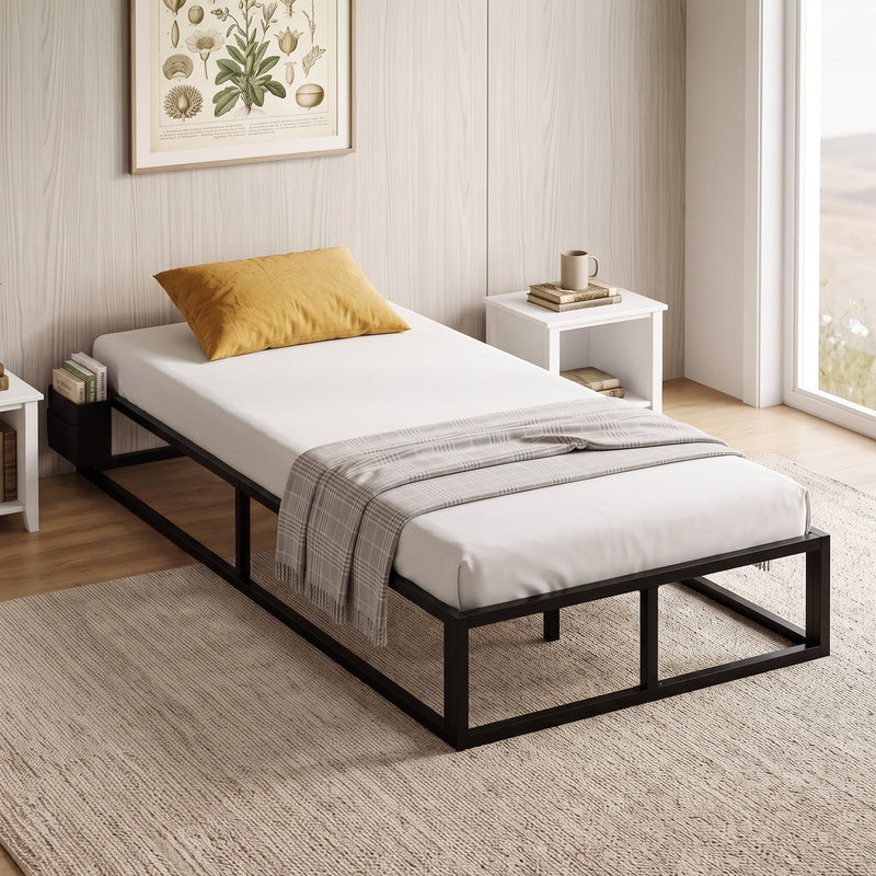 Single bed frame made up with a mattress and mustard pillow in a bedroom, with books in the side storage bag