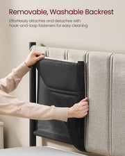 Two hands lifting the beige fabric cover away from the headboard to show the hook-and-loop backing behind it