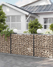 Stone gabion base running along a white house wall beside a downpipe