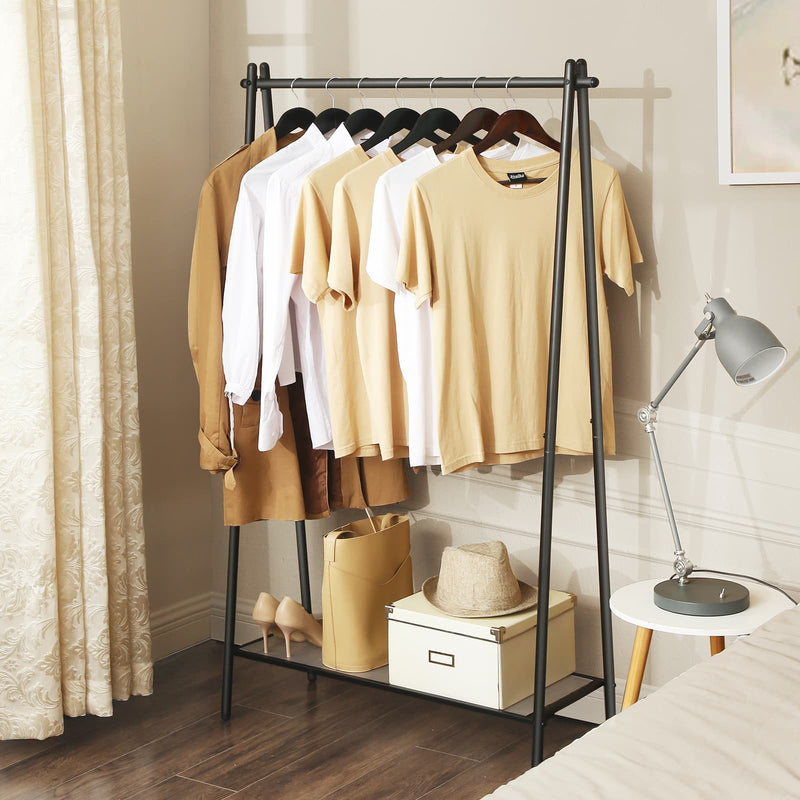 Black clothes rack against a cream wall with curtains, a desk lamp and a side table