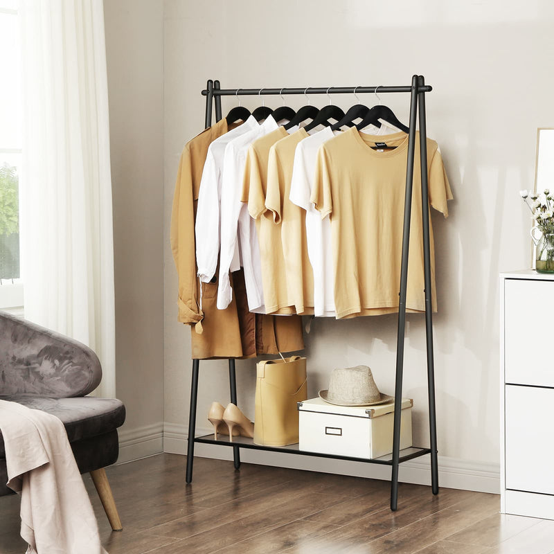 Single rod garment rack in a living room corner with a grey armchair and wood floor