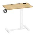 Golden Oak sit-stand overbed table with a white T-shaped frame and black side cup holder, studio view