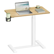 The overbed table holding an open laptop, a coffee cup and a notebook with a drink in the side cup holder