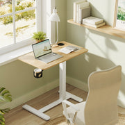 The table set up by a window in a green painted room with a laptop, desk lamp and plant