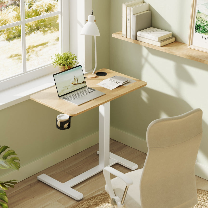 The table set up by a window in a green painted room with a laptop, desk lamp and plant