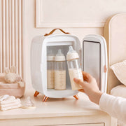 Hand taking a baby bottle from the open white fridge in a nursery