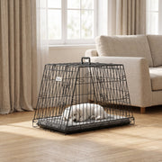 Small white dog asleep on a mat inside the crate in a living room