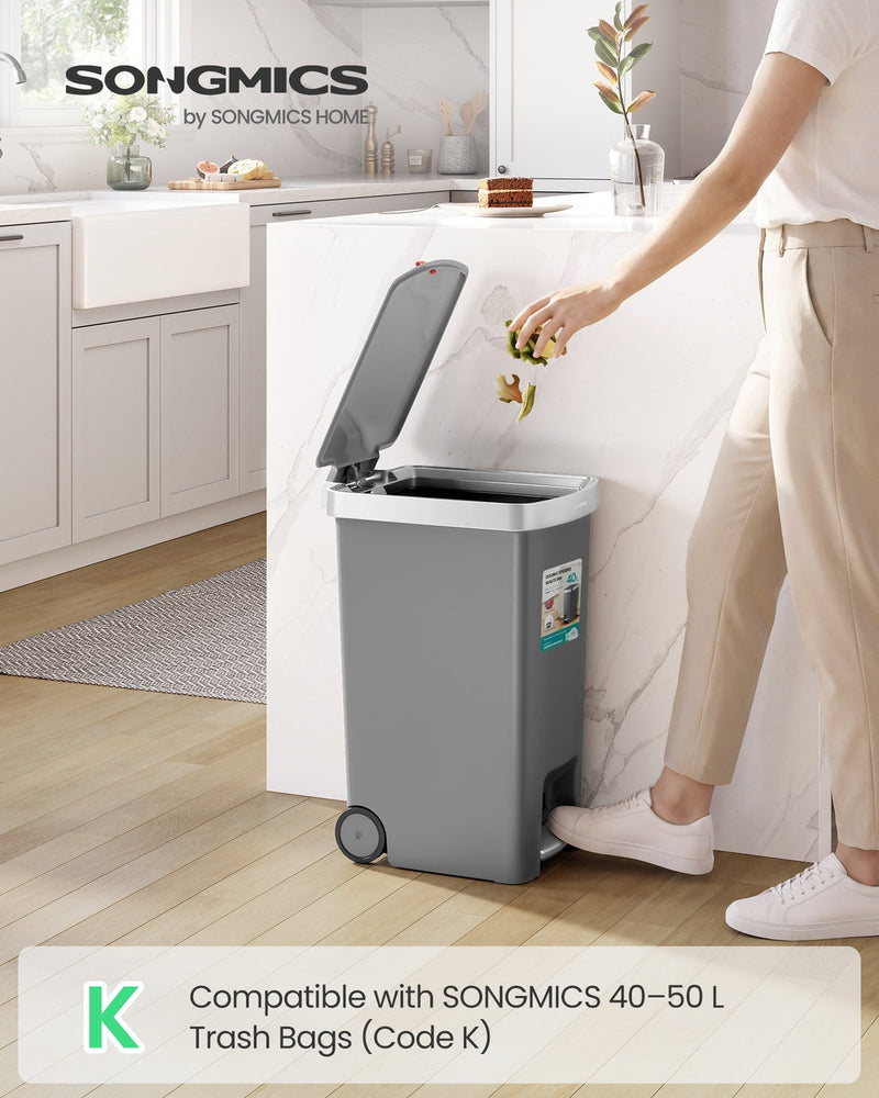 Person stepping on the pedal of a grey 40L kitchen bin to drop food scraps in