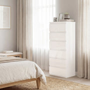Tall white chest of drawers beside a bed near a sunlit curtained window
