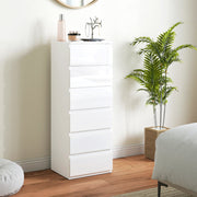 White 6-drawer chest of drawers in a bedroom beside a potted palm and a mirror