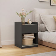 Bedside table styled with a vase of flowers and a small clock on top, beside a bed