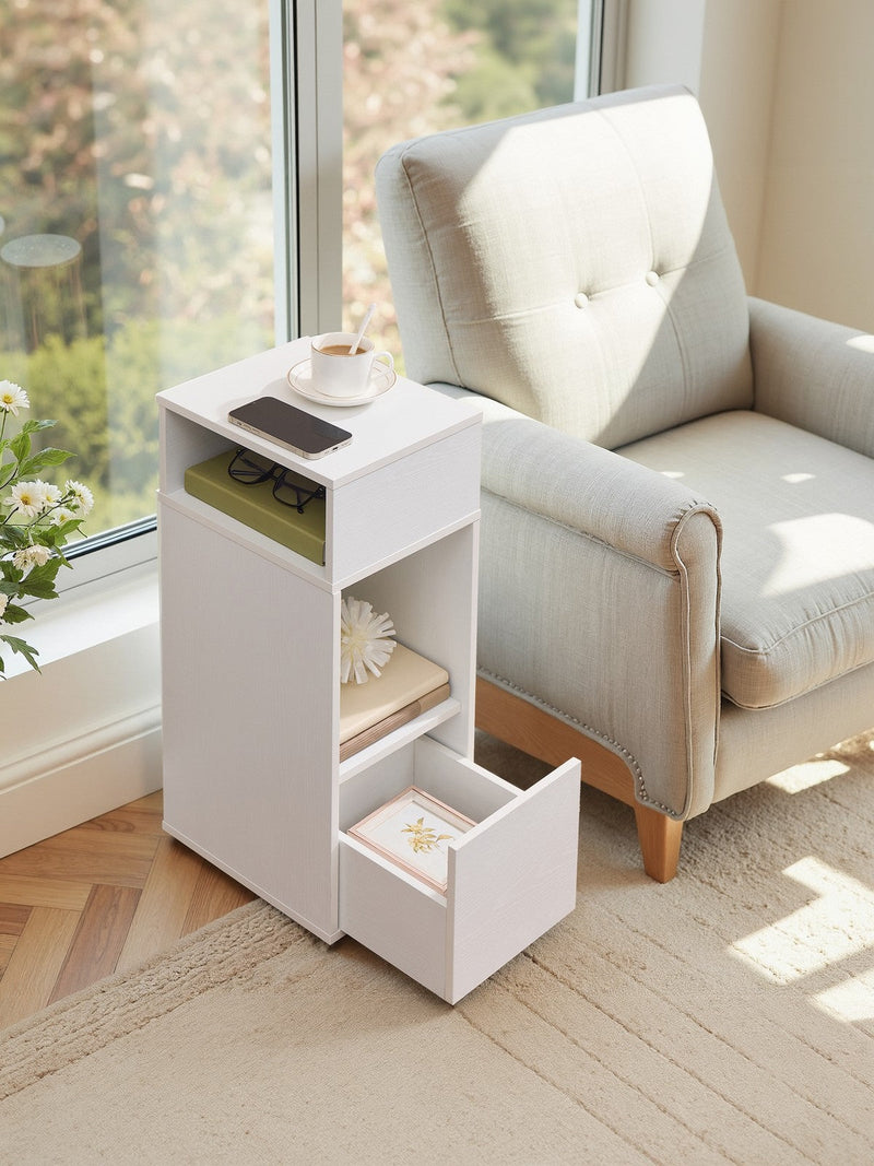 Bedside table beside an armchair by a window with the bottom drawer pulled open