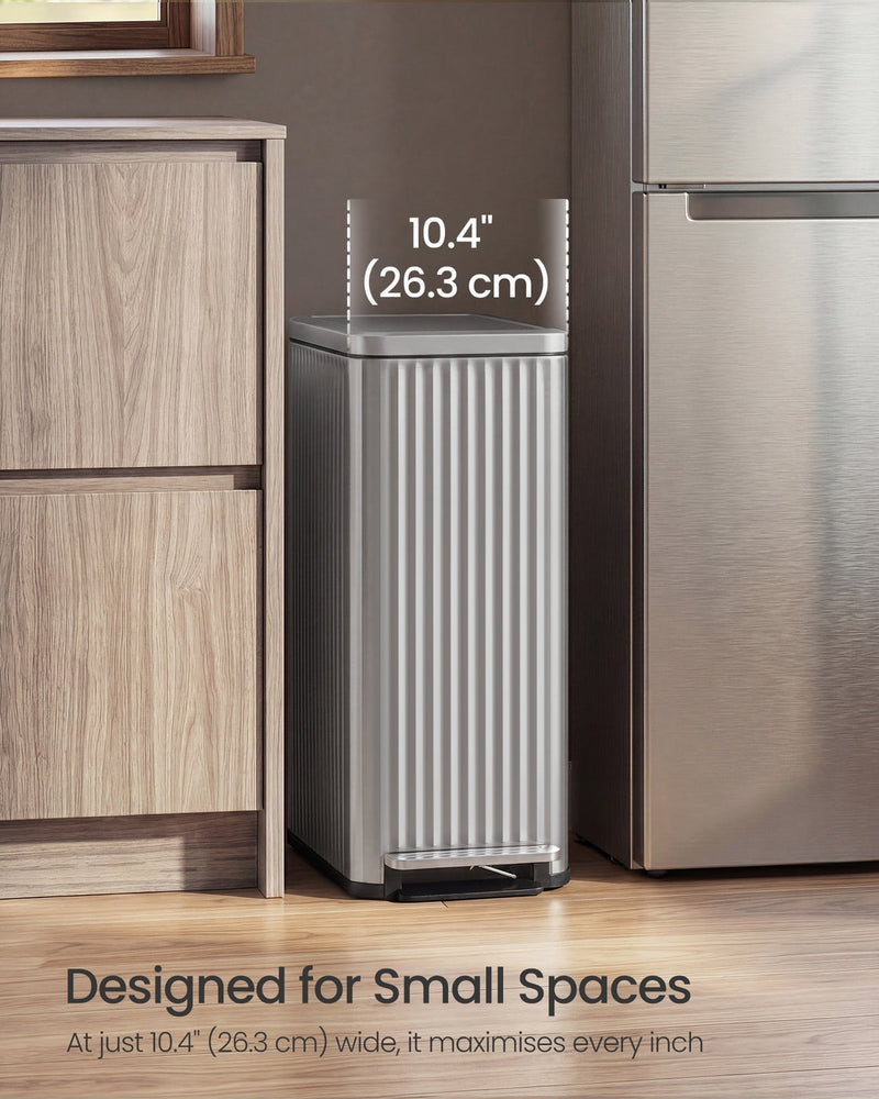 The silver Songmics 50 L pedal bin slotted into a narrow 26.3 cm gap between a wooden kitchen cabinet and a fridge