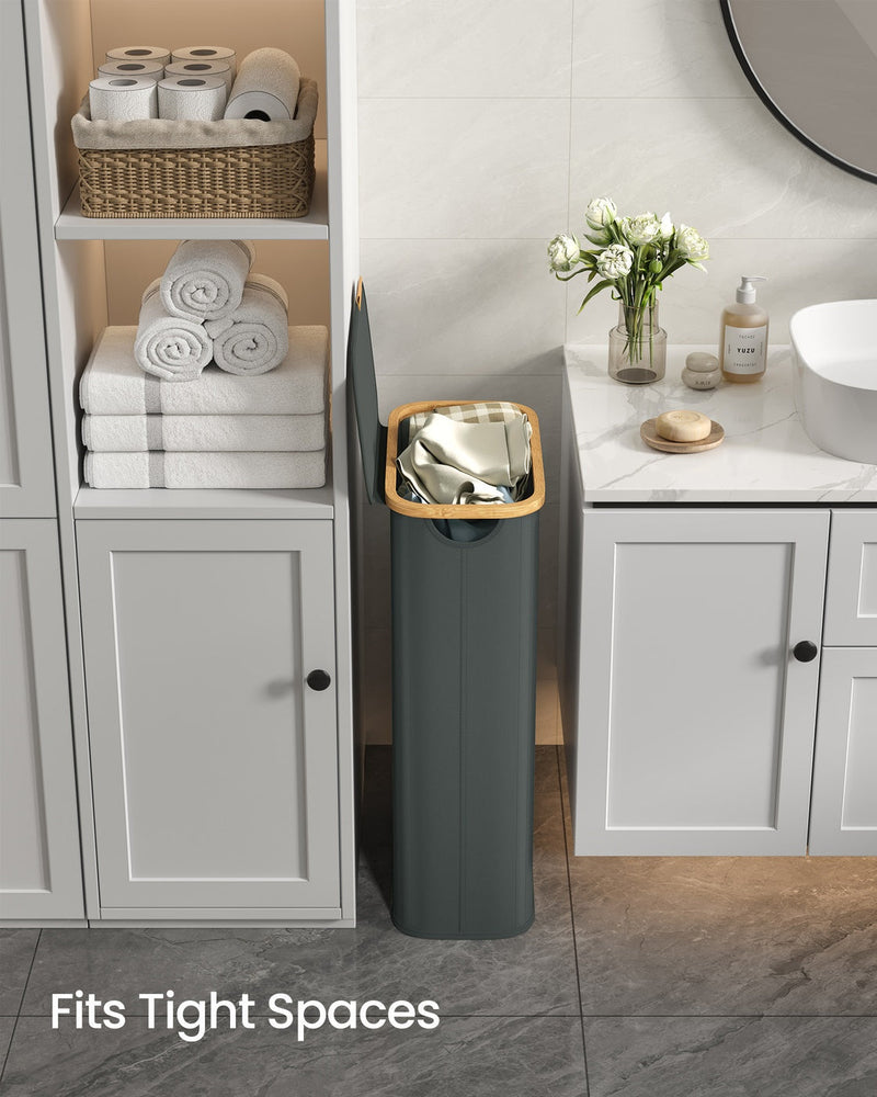 The slim hamper fitting into a narrow bathroom gap below a round wall mirror