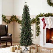 Slim pencil Christmas tree beside a fireplace with stockings and garland