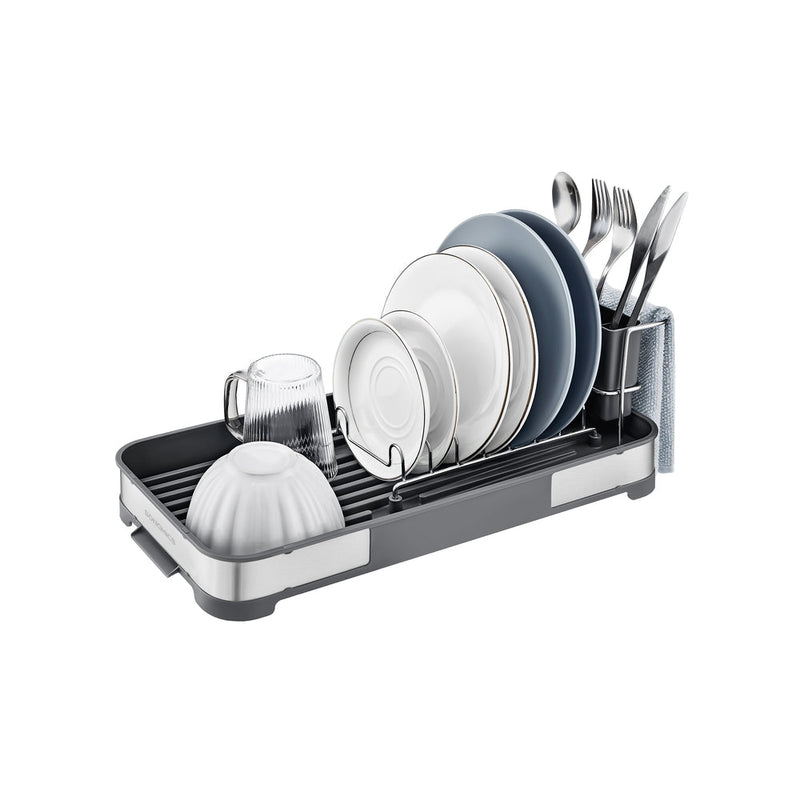 The dish rack loaded with white and blue plates, a bowl, a glass mug and cutlery in the holder