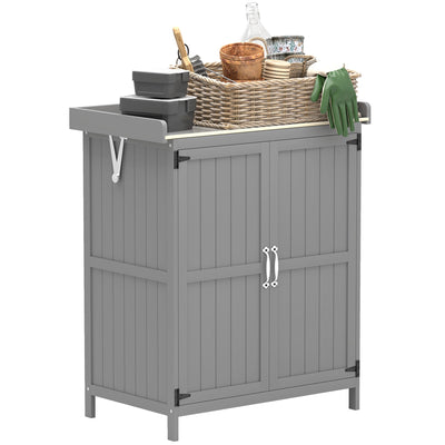 Grey wooden garden tool shed with stainless steel worktop holding plant pots, a wicker basket and gardening gloves
