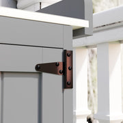 Close-up of the dark metal T-hinge fixing the shed door to the grey wooden side panel