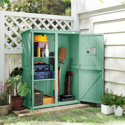Green wooden garden shed open beside white cladding, holding a hose, paint tins, a toolbox and a broom