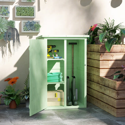 Green shed open against a cream wall holding a drill, a hose, wellington boots and garden bags