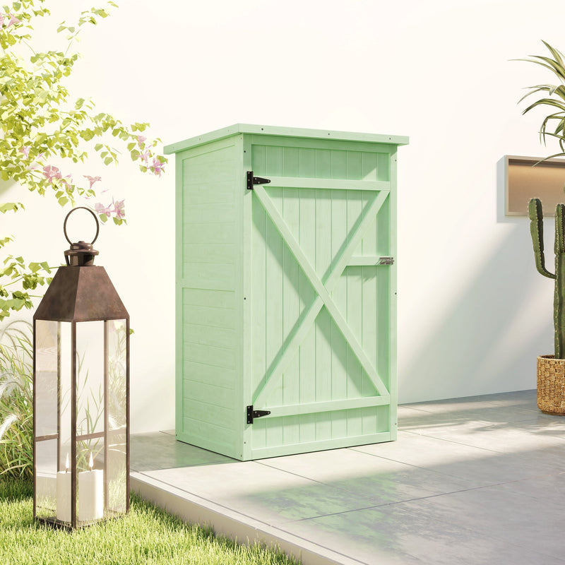Green wooden shed closed on a patio beside a copper lantern and a potted plant