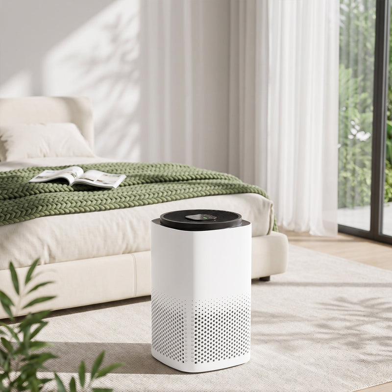 Air purifier at the foot of a bed in a bright bedroom