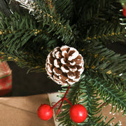 Close-up of a snow-dipped pinecone and two red berries on a green branch