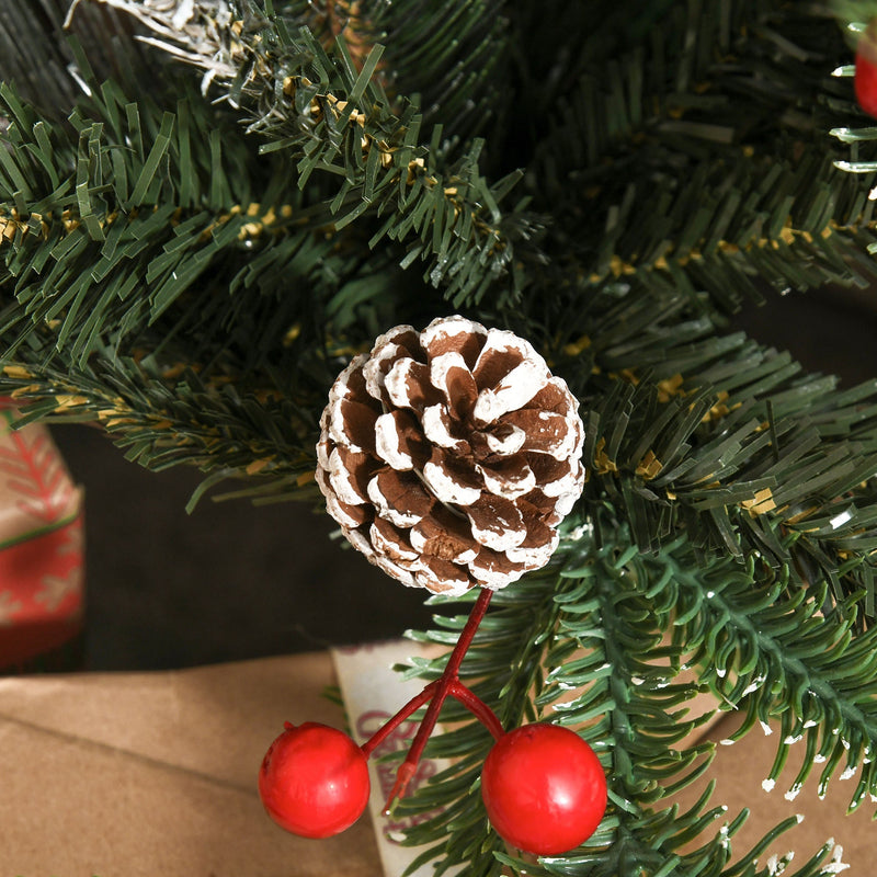 Close-up of a snow-dipped pinecone and two red berries on a green branch