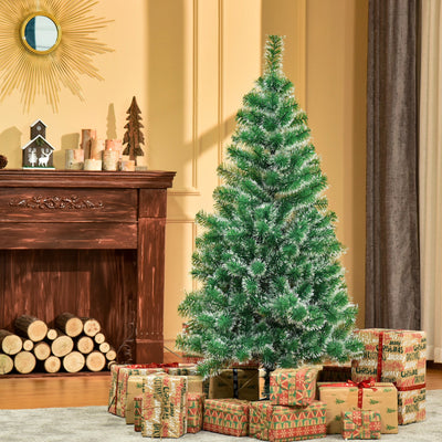 Snow-flocked Christmas tree beside a wooden fireplace with stacked logs and wrapped gifts