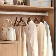 Wardrobe rail fitted with dark walnut wood hangers holding folded and hung clothes