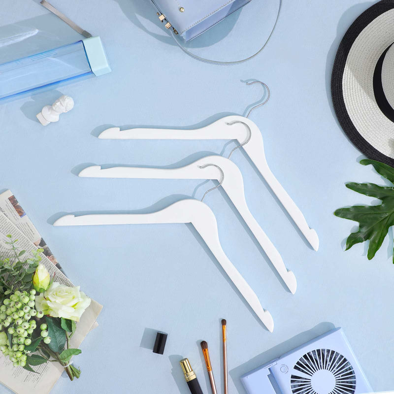 Three white wooden hangers laid on a blue background with a sun hat and flowers