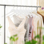 White wooden hangers on a rail holding lace dresses and a beige jacket