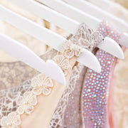 Close-up of the shoulder notch on a white hanger holding a lace dress strap