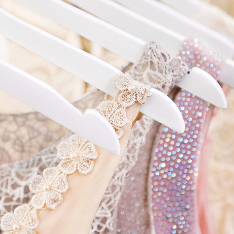 Close-up of the shoulder notch on a white hanger holding a lace dress strap