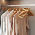 Lifestyle photo of wooden hangers holding clothes on a wardrobe rail