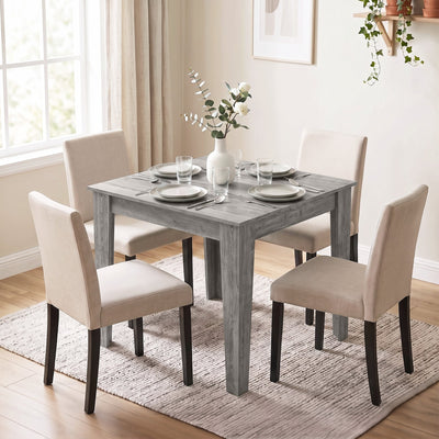 Grey dining table set for a meal with four cream upholstered dining chairs, chairs sold separately