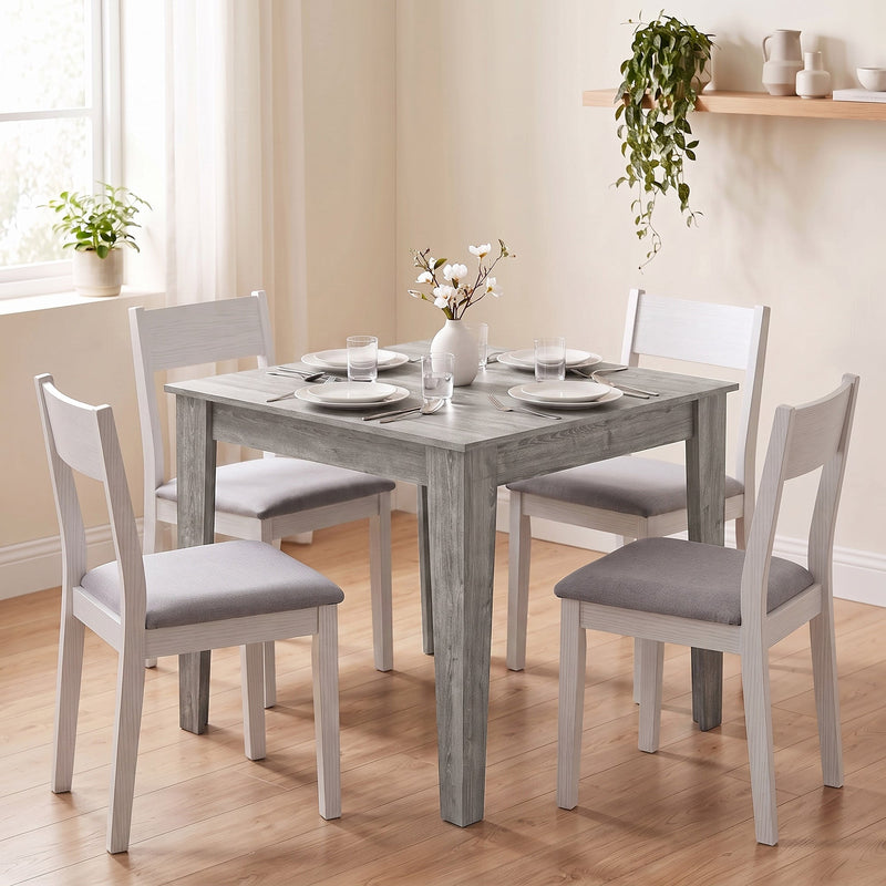 Dining table styled with white dining chairs, place settings and flowers