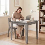 Woman using the table as a home office desk with a laptop and books