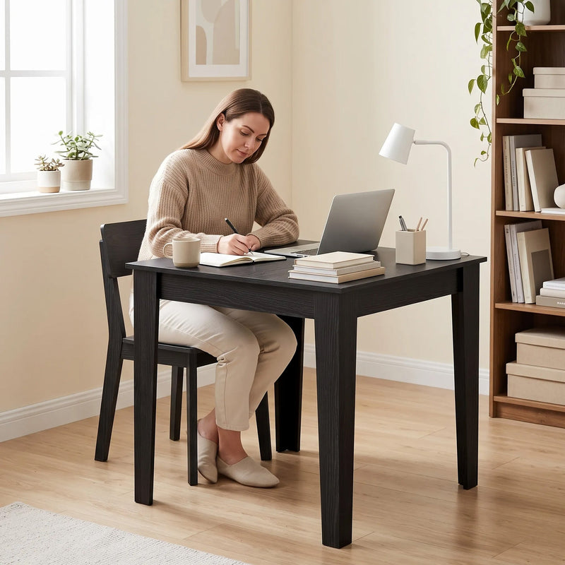 Black Wood Effect dining table used as a home workspace with a laptop and desk lamp