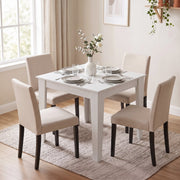 White dining table set for four with beige upholstered chairs