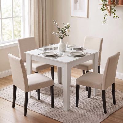 White dining table set for four with beige upholstered chairs