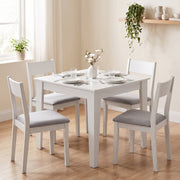 White dining table with four matching chairs in a dining room