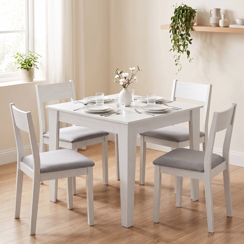 White dining table with four matching chairs in a dining room