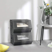 Pair of grey storage boxes stacked on a floor beside a chair and a yellow cushion