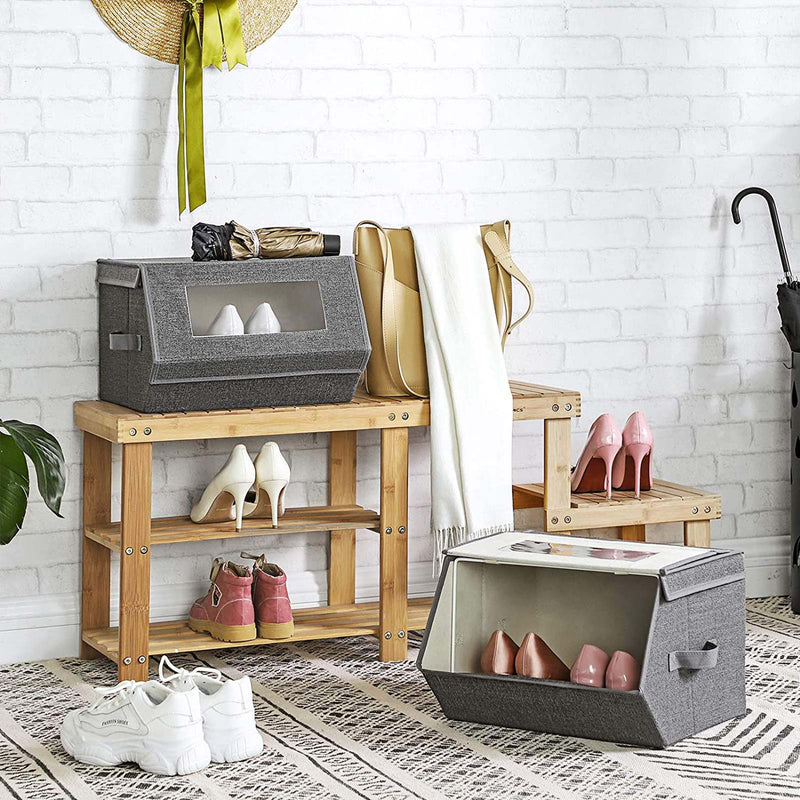 Grey storage box on a hallway bench under a brick wall with bags and an umbrella