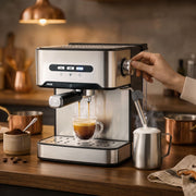 Hand turning the frothing knob as espresso pours into a glass on a wooden worktop