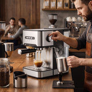 Barista steaming milk in a jug beside the espresso machine in a coffee shop