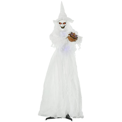 Standing white Halloween witch in a long gown holding a small carved pumpkin
